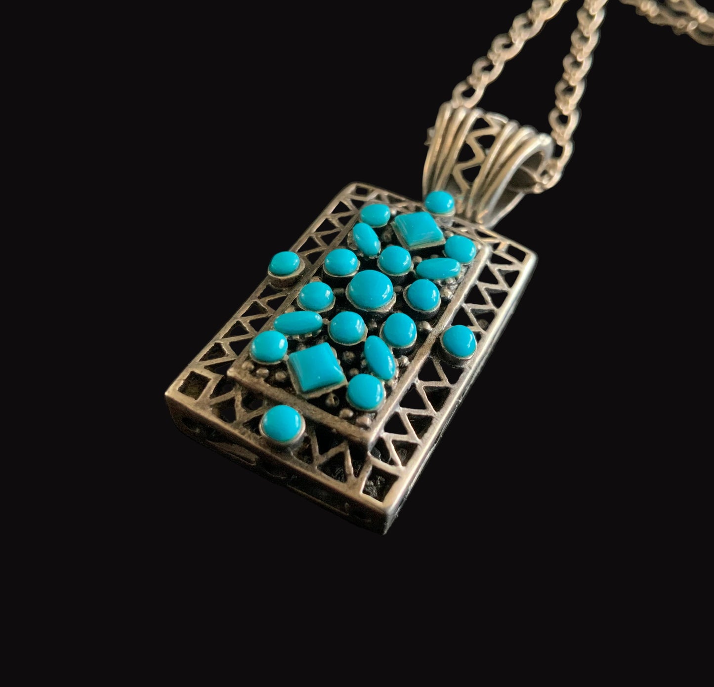 Necklace with a rectangular pendant featuring turquoise stones on a black background