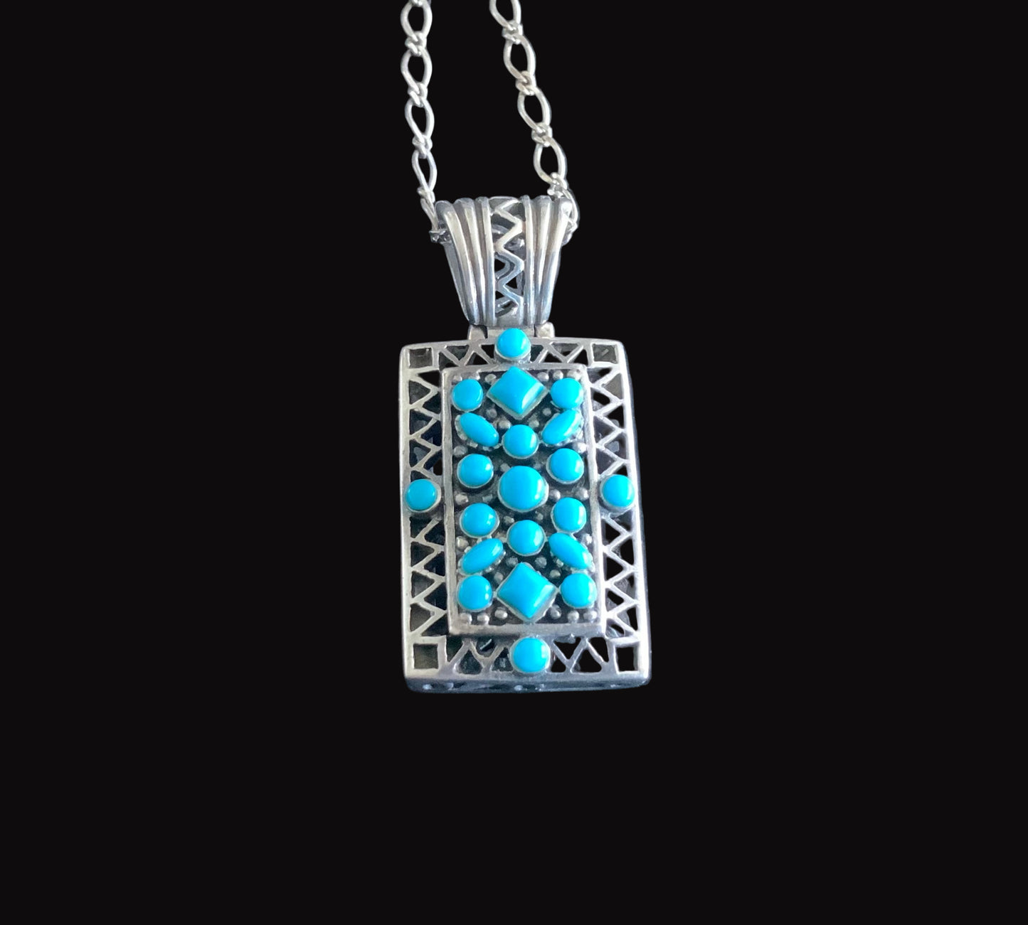 Silver pendant with turquoise stones on a black background
