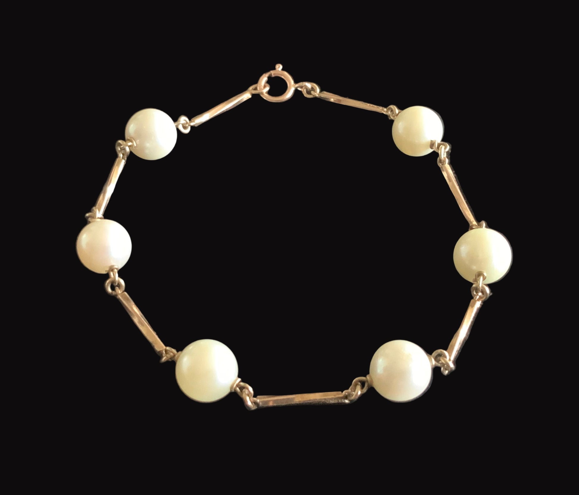 Pearl bracelet with gold chain on a black background