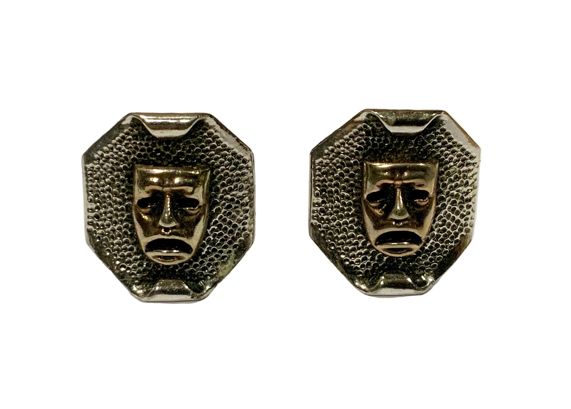 Pair of metallic face-shaped earrings on a white background