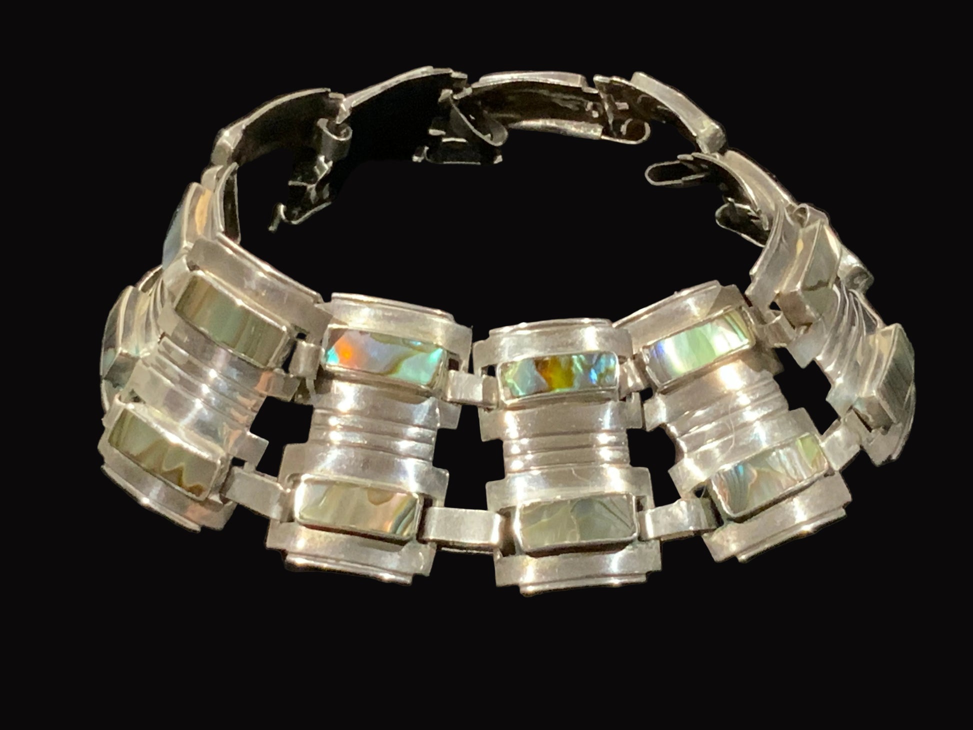 Silver bracelet with iridescent stones on a black background